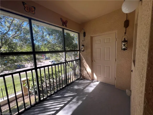 Covered porch featuring a screen enclosure, metal railings, textured wall finish, and wall-mounted exterior lanterns