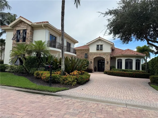 Mediterranean / spanish house with stucco siding, stone siding, a tile roof, and decorative driveway