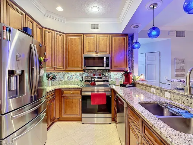 Kitchen featuring wood cabinetry, stainless steel appliances, granite countertops, and a decorative tile backsplash