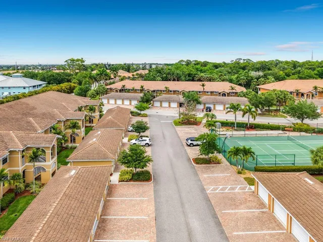 Community features multiple residential buildings with tile roofs, an asphalt paved road, and brick paver parking areas