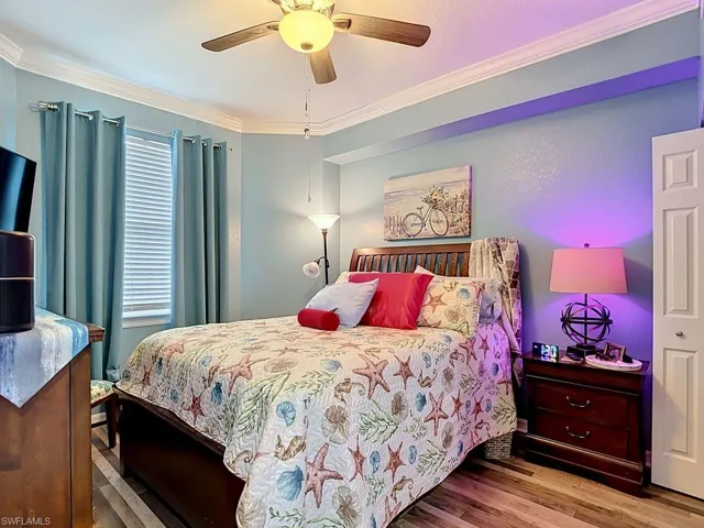 Bedroom featuring light blue walls, wood-finish flooring, and crown molding