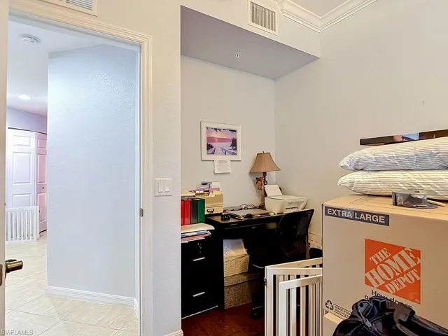 Interior hallway with tiled flooring and white trimwork, featuring a recessed ceiling and crown molding