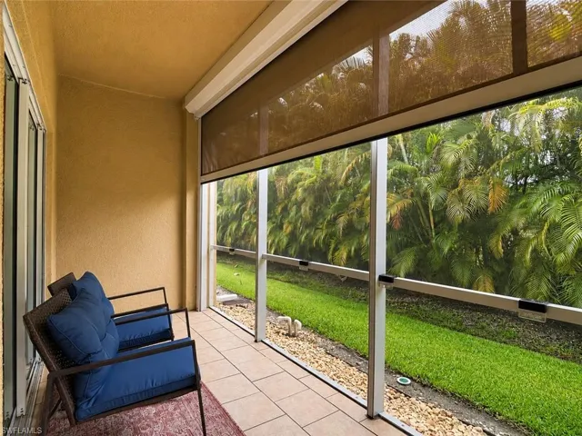 Screened lanai featuring tile flooring, textured stucco walls, and a retractable Hurricane Shade