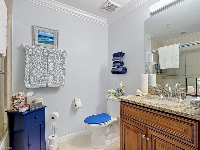 Bathroom featuring a single vanity with a granite-style countertop, undermount sink, and wood-finish cabinetry