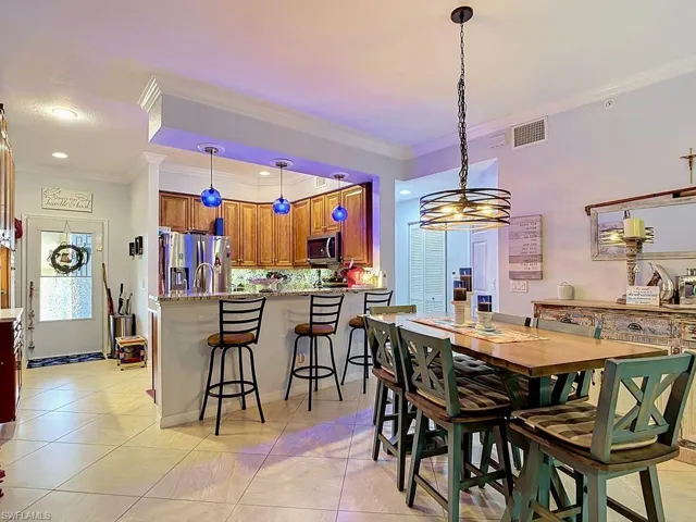 Spacious open-concept living area featuring a kitchen island with seating, pendant lighting, stainless steel appliances, and wood-finish cabinetry