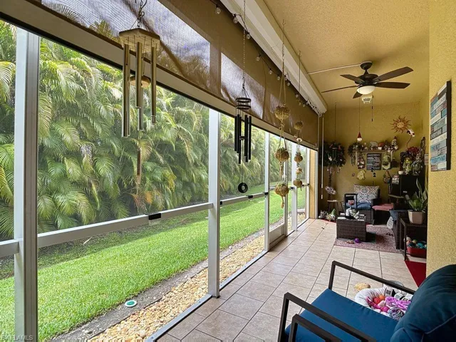 Screened patio featuring tile flooring, a ceiling fan, and lush exterior landscaping