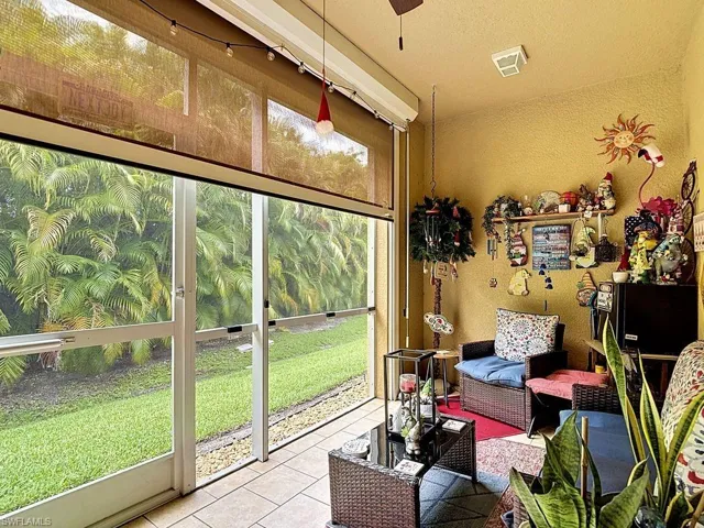 Screened-in patio featuring tiled flooring, a textured yellow wall, and direct access to an exterior green space