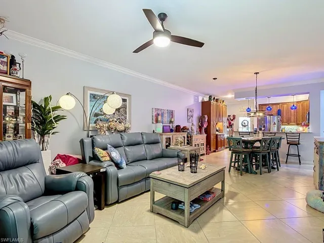 Open-concept living area with large-format tile flooring and crown molding