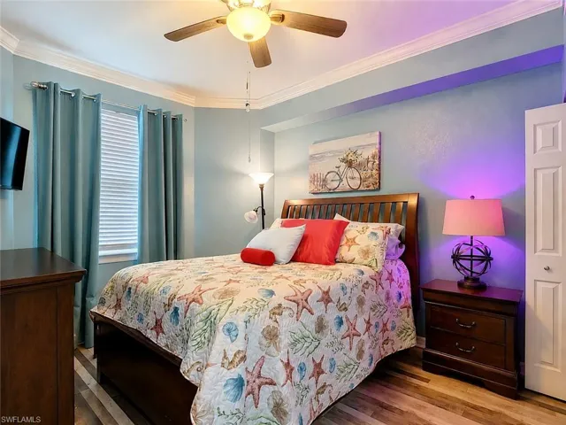 Bedroom featuring wood-finish flooring, a ceiling fan, a window with blinds, and crown molding