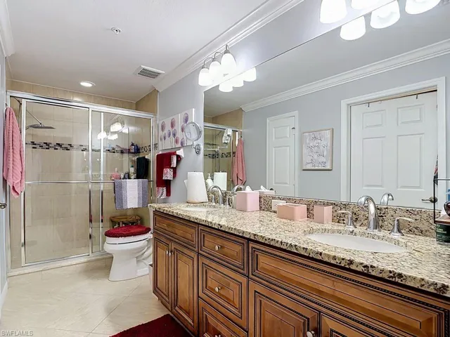 Bathroom featuring a dual vanity with granite countertops, polished chrome fixtures, and rich wood cabinetry