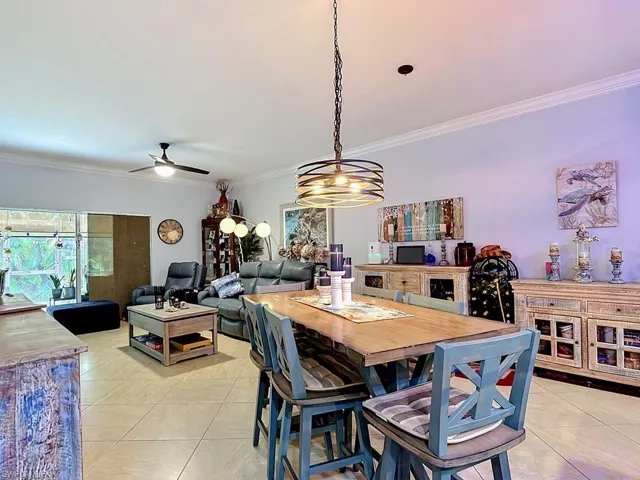 Open-concept living space with tile flooring throughout, crown molding, and a modern ceiling fan