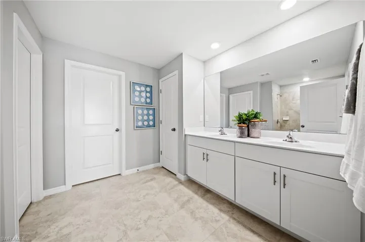 Bathroom featuring a double vanity with white cabinetry, light-toned countertop, and dual sinks