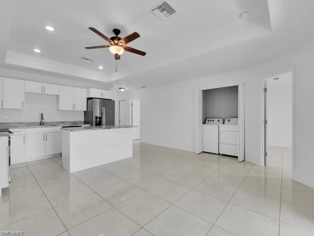 Kitchen featuring a tray ceiling, white cabinetry, recessed lighting, stainless steel refrigerator with ice dispenser, and light tile patterned floors