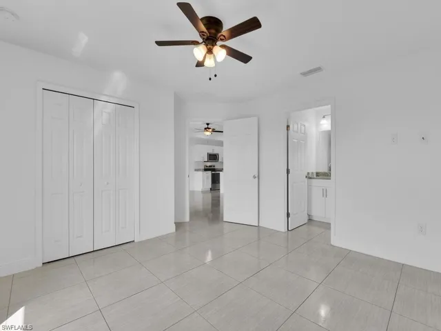 Primary Unfurnished bedroom with a ceiling fan, on suite and large closet
