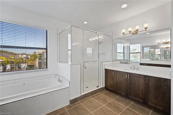 Full bathroom featuring vanity, a bath, a shower stall, dark tile patterned flooring, and recessed lighting
