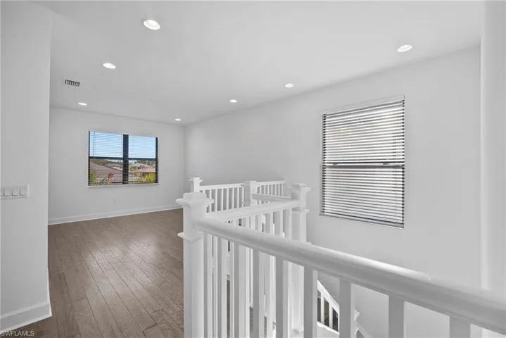 Hall featuring hardwood / wood-style floors, recessed lighting, and an upstairs landing