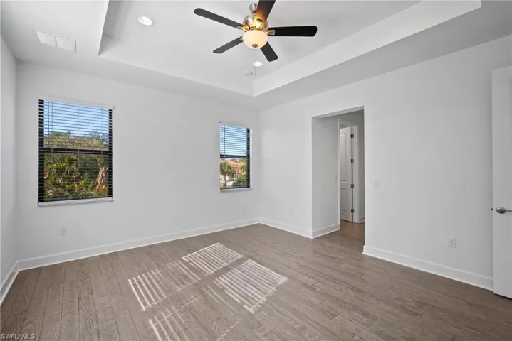 Spare room with a raised ceiling, recessed lighting, wood finished floors, and ceiling fan