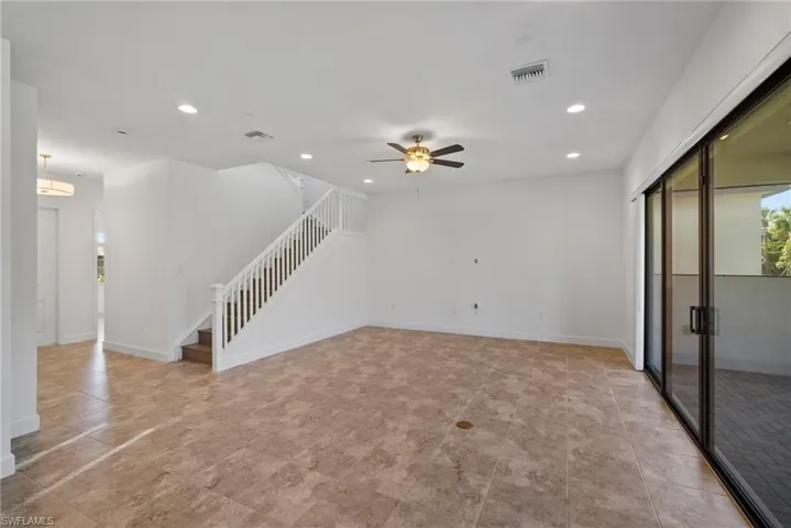Unfurnished living room with recessed lighting, ceiling fan, and stairway
