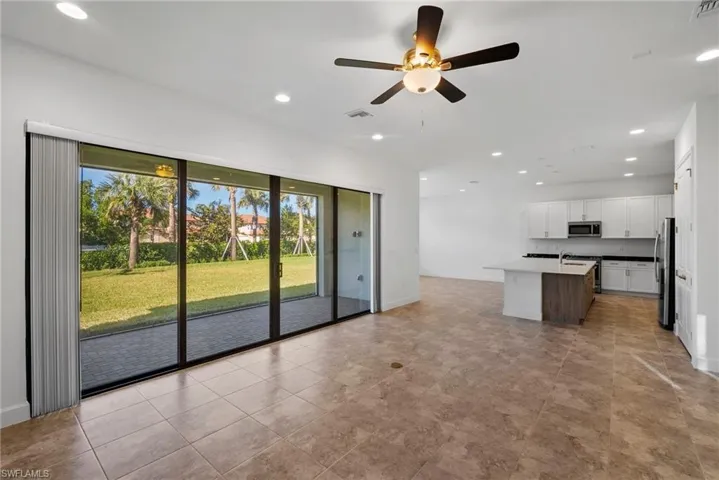 Kitchen featuring an island with sink, open floor plan, recessed lighting, white cabinets, and a ceiling fan