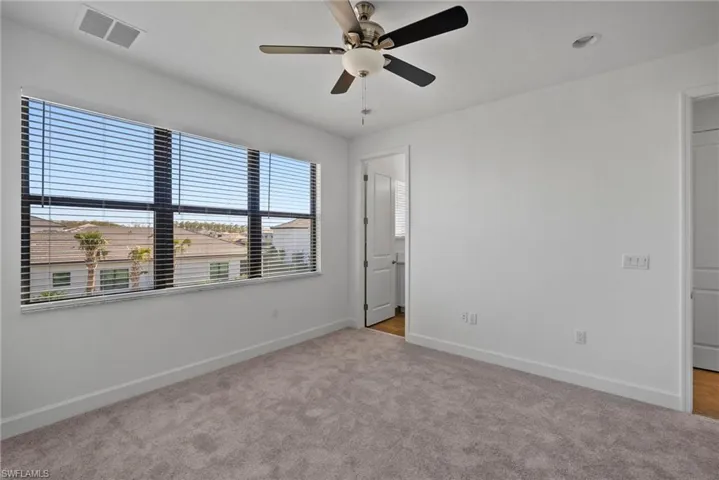 Unfurnished bedroom with ceiling fan and light colored carpet