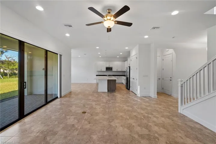 Kitchen with open floor plan, white cabinets, a ceiling fan, a kitchen island, and light countertops