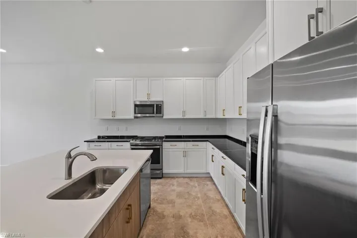 Kitchen with stainless steel appliances, white cabinetry, recessed lighting, and brown cabinets