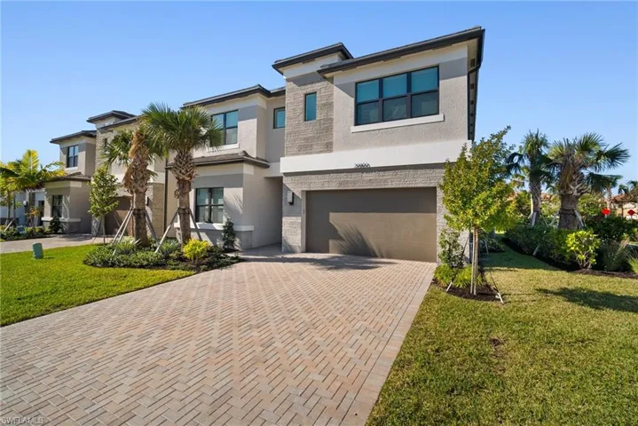 View of front of property featuring stucco siding, a front yard, decorative driveway, and an attached garage