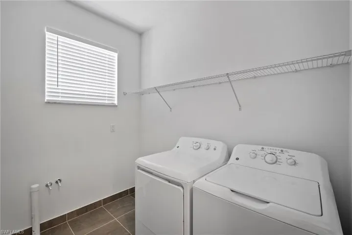 Laundry room featuring dark tile patterned flooring and separate washer and dryer