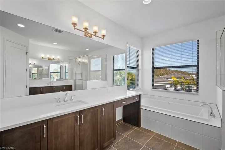 Bathroom with a garden tub, vanity, a stall shower, dark tile patterned flooring, and recessed lighting
