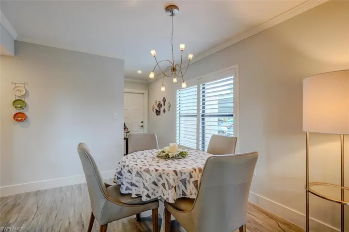 Dining area featuring light wood-type flooring, crown molding, and a chandelier