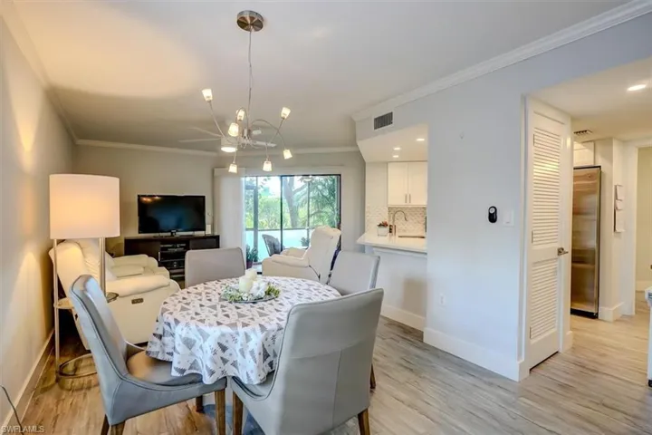 Dining space with light hardwood / wood-style floors, ornamental molding, and an inviting chandelier