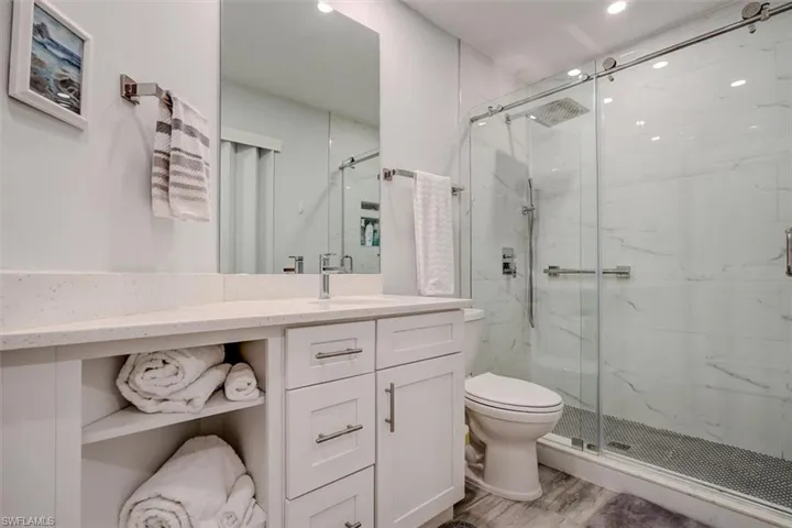 Bathroom featuring vanity, hardwood / wood-style flooring, toilet, and a shower with door