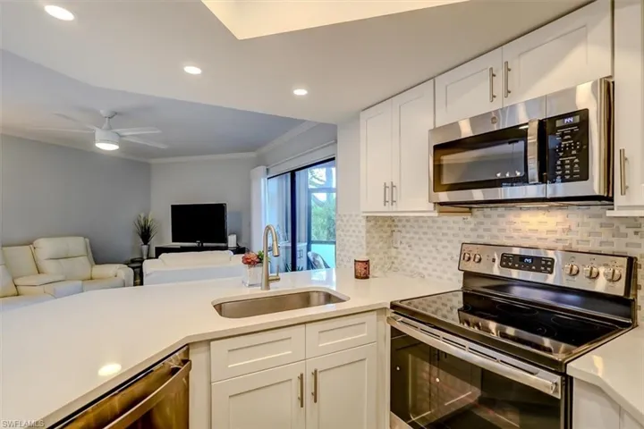 Kitchen with white cabinetry, sink, ceiling fan, appliances with stainless steel finishes