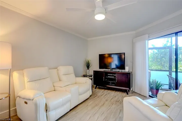 Living room with light wood-type flooring, ceiling fan, and crown molding