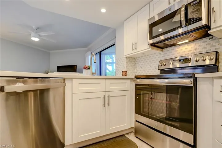 Kitchen featuring white cabinets, stainless steel appliances, tasteful backsplash