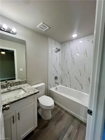 Full bathroom with toilet, shower / tub combination, wood-type flooring, vanity, and ceiling fan