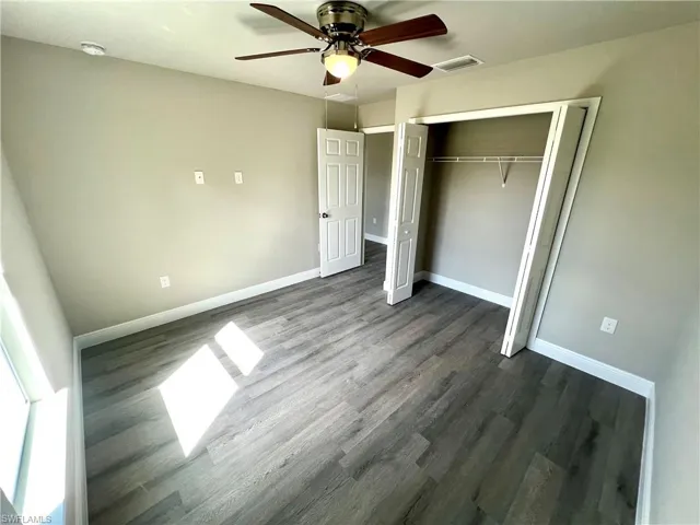 Unfurnished bedroom featuring dark hardwood / wood-style flooring, a closet, and ceiling fan