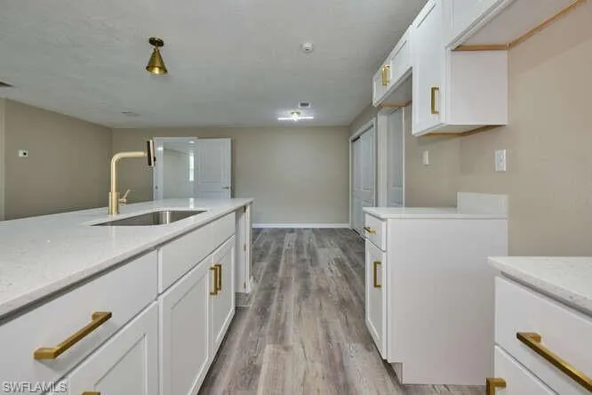 Kitchen with white cabinets, light wood-type flooring, and sink