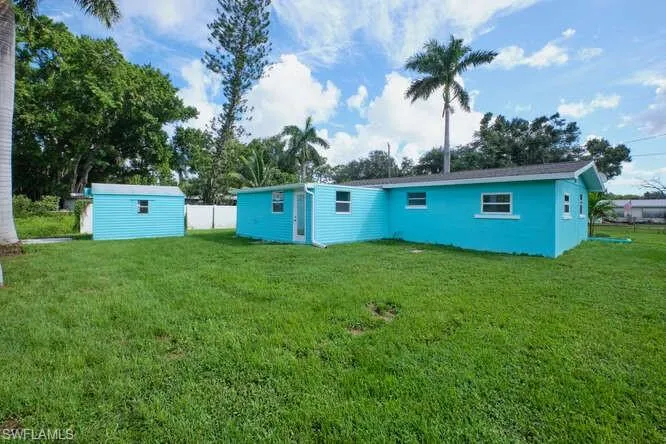 Back of house with a shed and a lawn