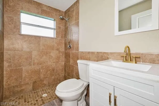 Bathroom featuring toilet, tiled shower, and vanity