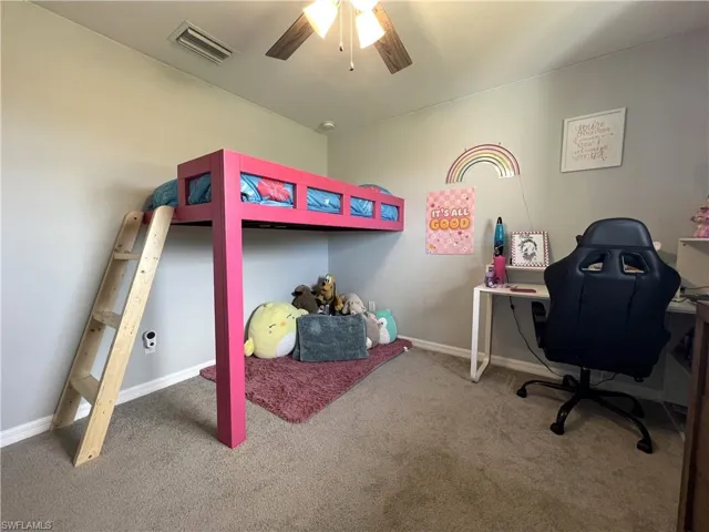 Bedroom with light colored carpet, a desk, and a ceiling fan