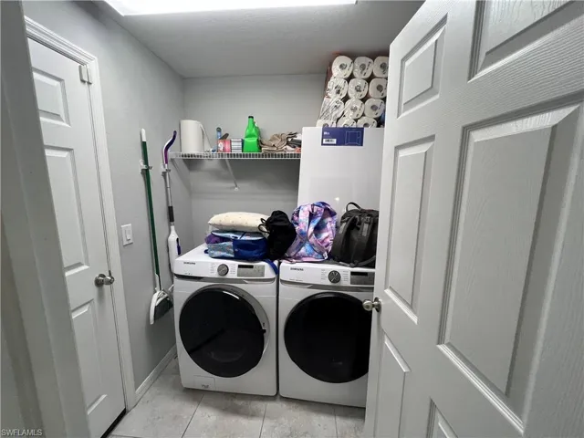 Laundry area with washer and clothes dryer and light tile patterned floors