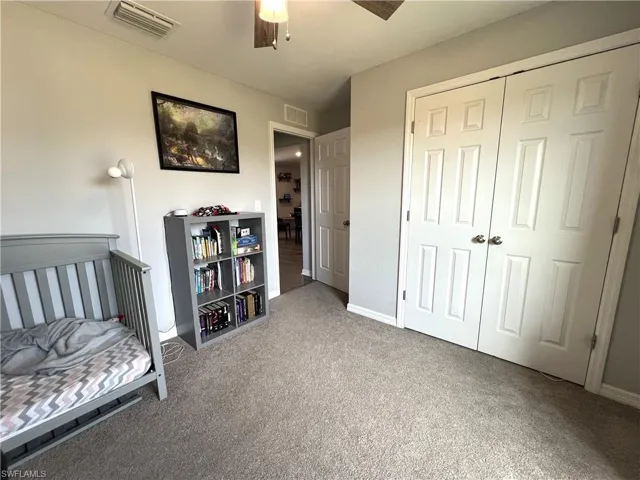 Bedroom featuring light carpet, a closet, and a ceiling fan