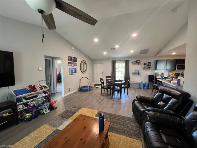 Living area with high vaulted ceiling, light wood-style floors, ceiling fan, and recessed lighting