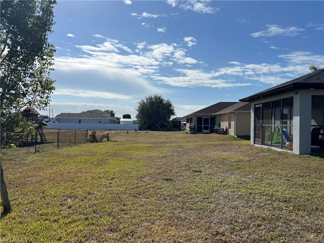 View of grassy yard featuring a sunroom