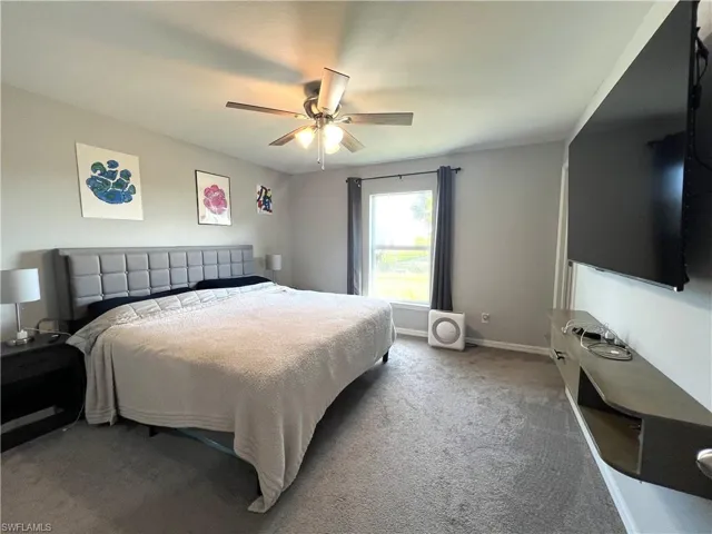 Carpeted bedroom with baseboards and a ceiling fan
