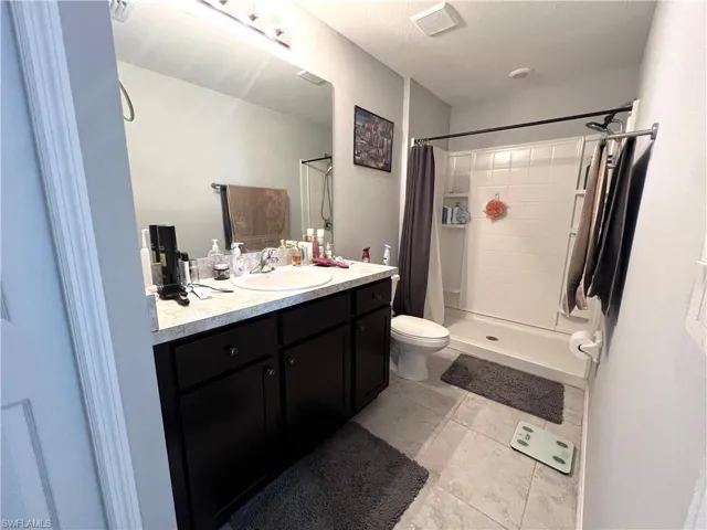 Bathroom with vanity, a stall shower, and light tile patterned floors