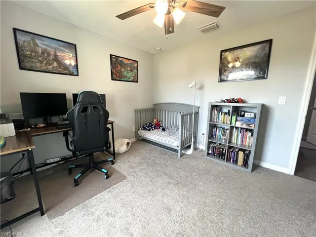 Bedroom with carpet floors, a nursery area, an office area, and a ceiling fan