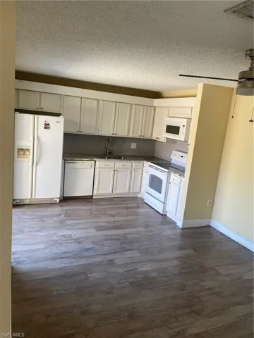 Kitchen from dining area featuring granite countertops, fridge, stove and dishwasher.
