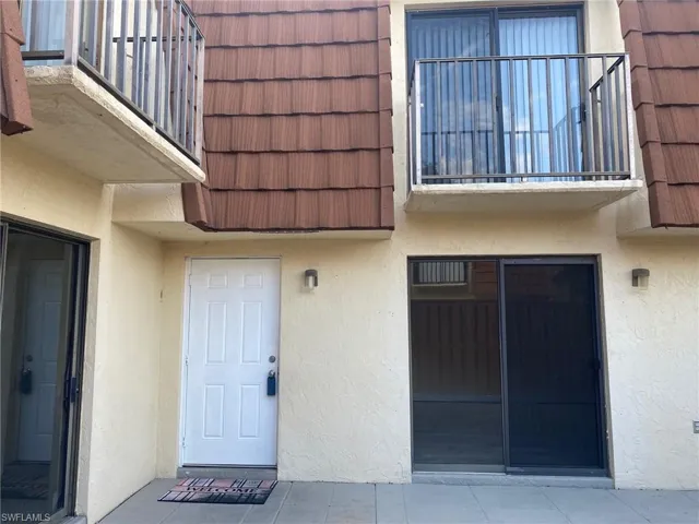 Property entrance with stucco siding and mansard roof